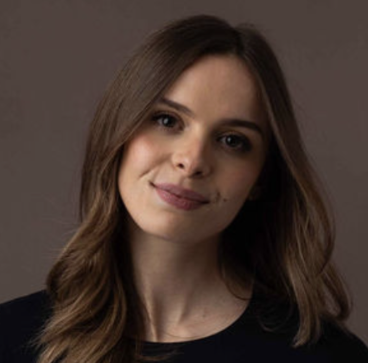 Portrait of a smiling woman with shoulder-length brown hair wearing a black top against a brown background, looking at the camera.
